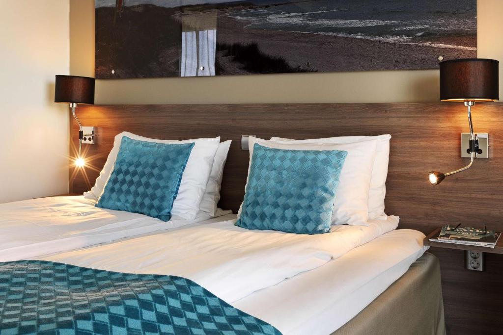 a hotel room with a bed with blue pillows at Scandic Stavanger Airport in Sola