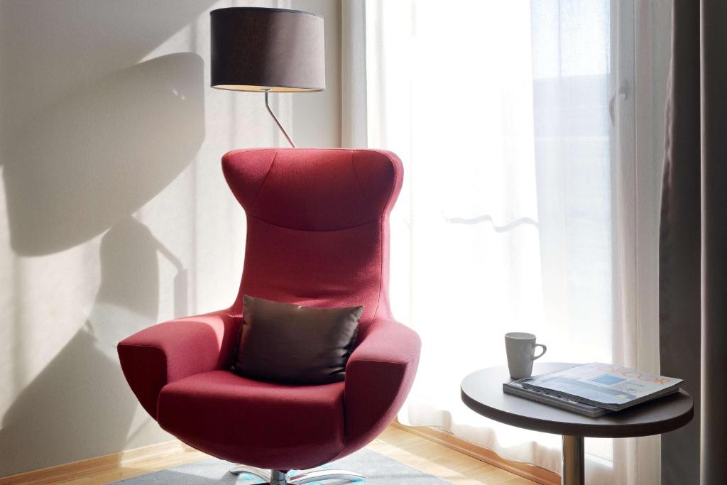 a red chair sitting next to a table with a lamp at Scandic Stavanger Airport in Sola