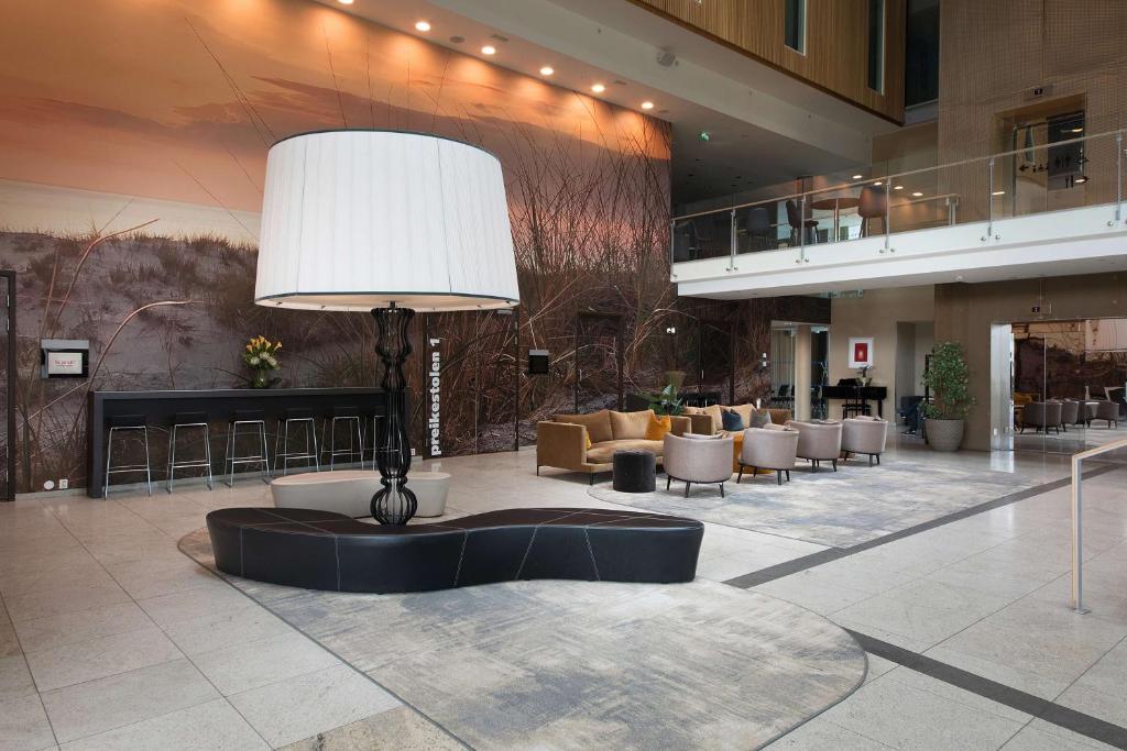 a lobby with a table and chairs in a building at Scandic Stavanger Airport in Sola
