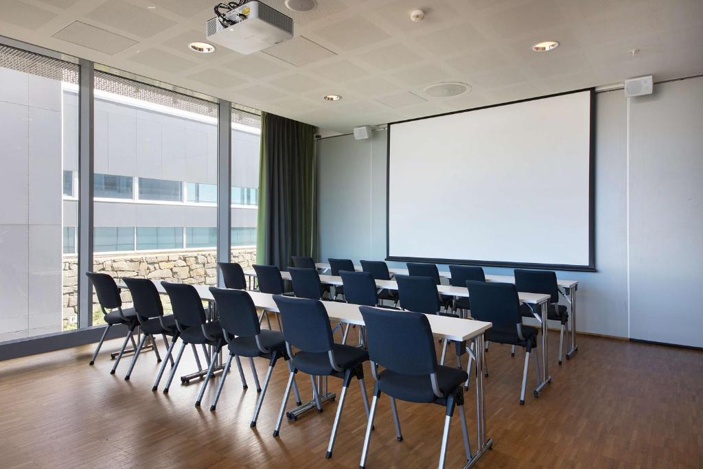 a conference room with a table and chairs and a screen at Scandic Stavanger Airport in Sola