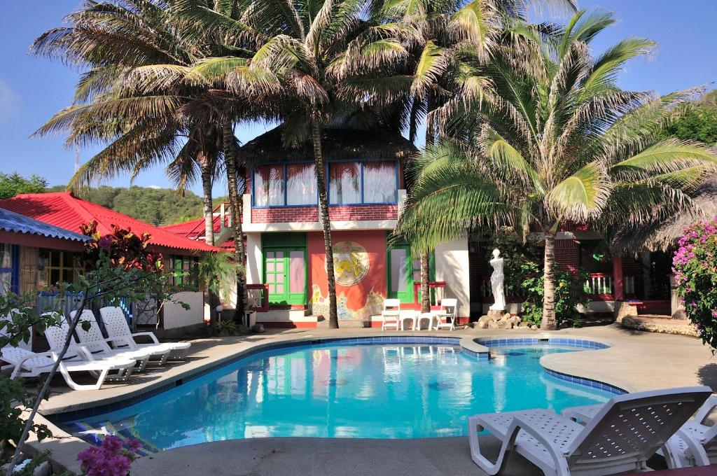 a swimming pool in front of a house with palm trees at Hosteria Canoa in Canoa