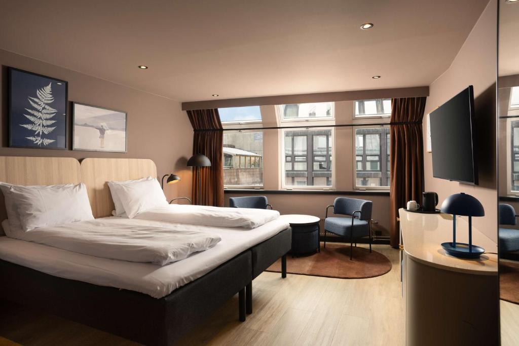 a hotel room with a bed and two windows at Scandic Victoria in Oslo