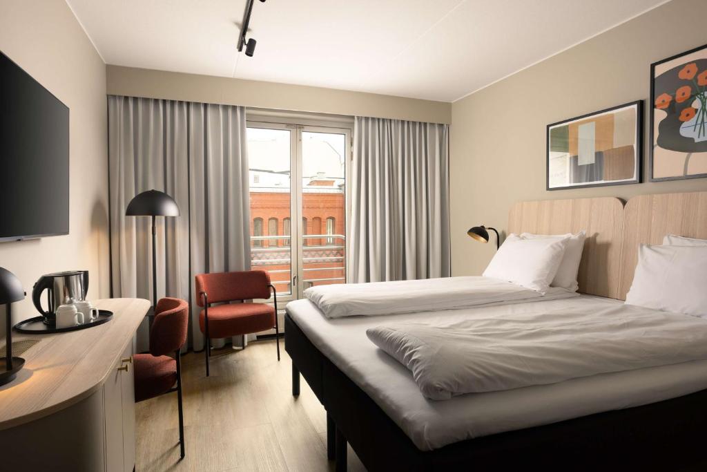 a hotel room with two beds and a desk at Scandic Victoria in Oslo