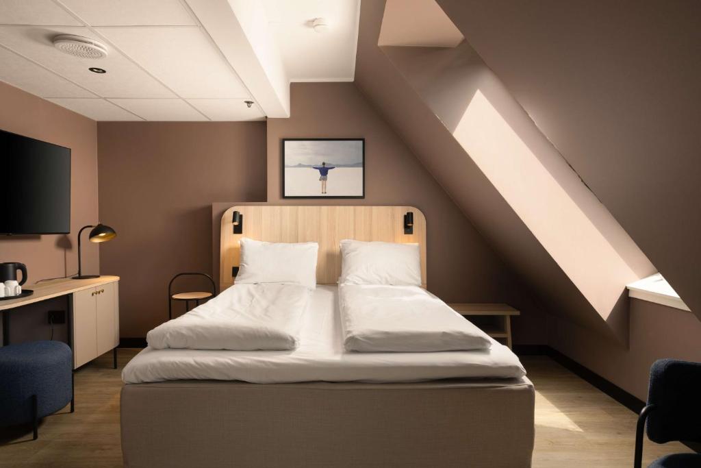 a bed in a room with a sloped ceiling at Scandic Victoria in Oslo