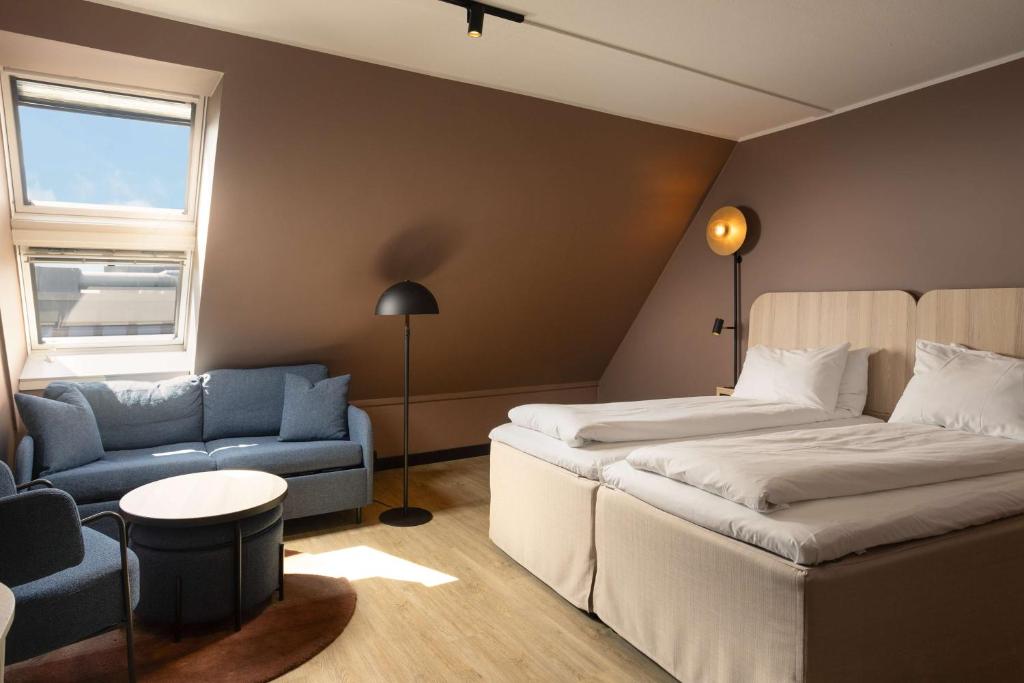 a hotel room with two beds and a couch and a chair at Scandic Victoria in Oslo