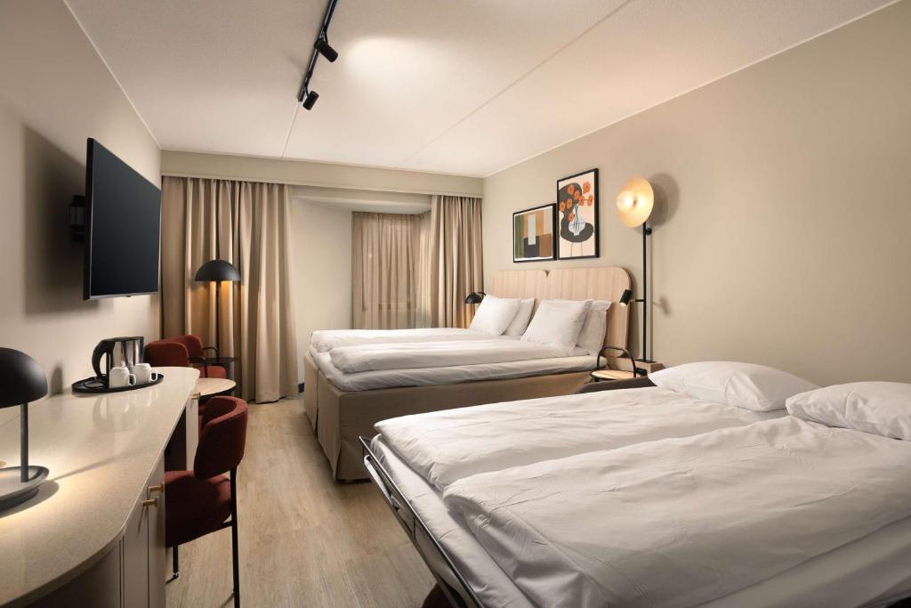 a hotel room with two beds and a television at Scandic Victoria in Oslo