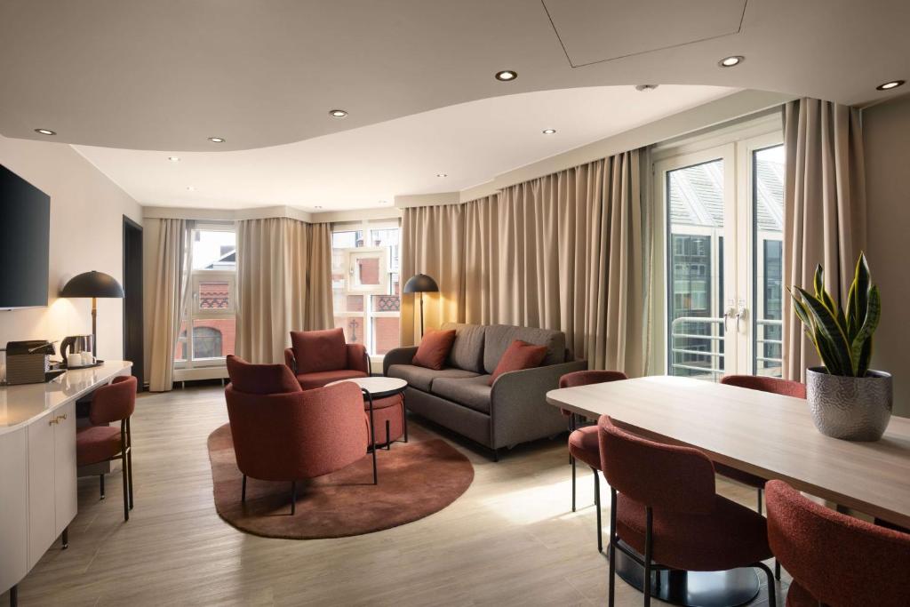 a living room with a couch and a table and chairs at Scandic Victoria in Oslo