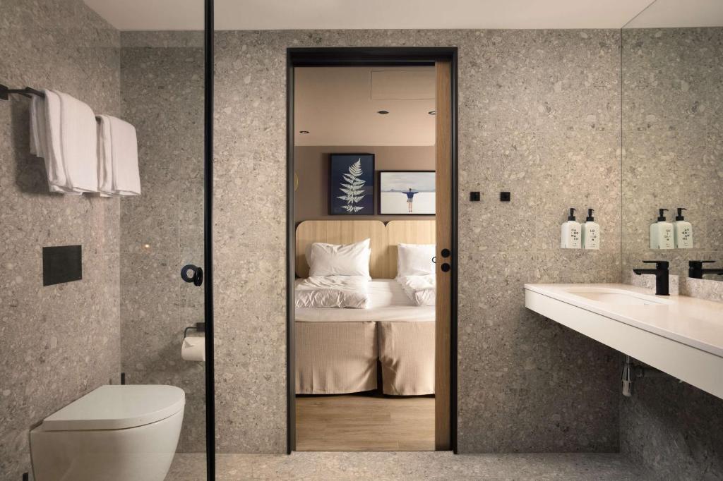a bathroom with a bed and a toilet and a sink at Scandic Victoria in Oslo
