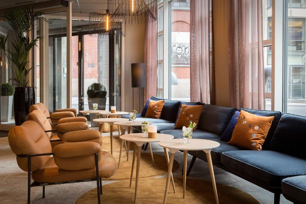 a living room with a blue couch and tables at Scandic Victoria in Oslo