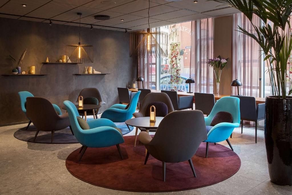 a waiting room with blue chairs and tables at Scandic Victoria in Oslo