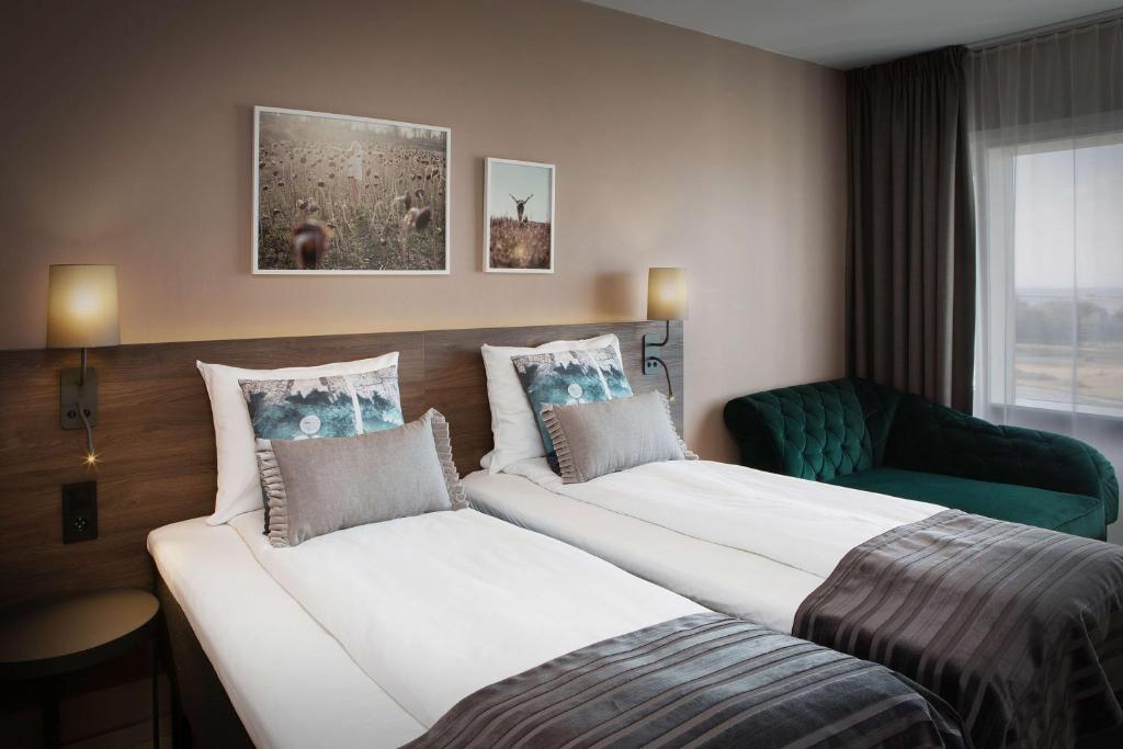 a hotel room with two beds and a chair at Scandic Hell in Hell