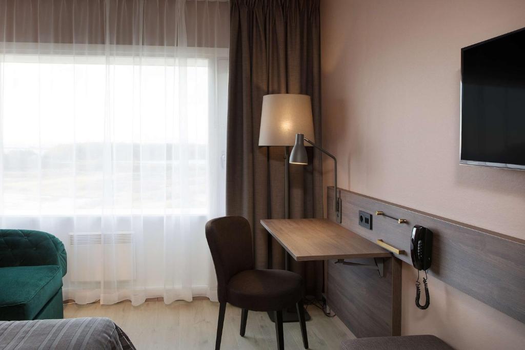 a hotel room with a desk and a television at Scandic Hell in Hell