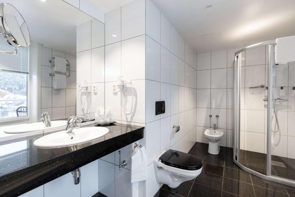 a white bathroom with two sinks and a toilet at Scandic Hell in Hell