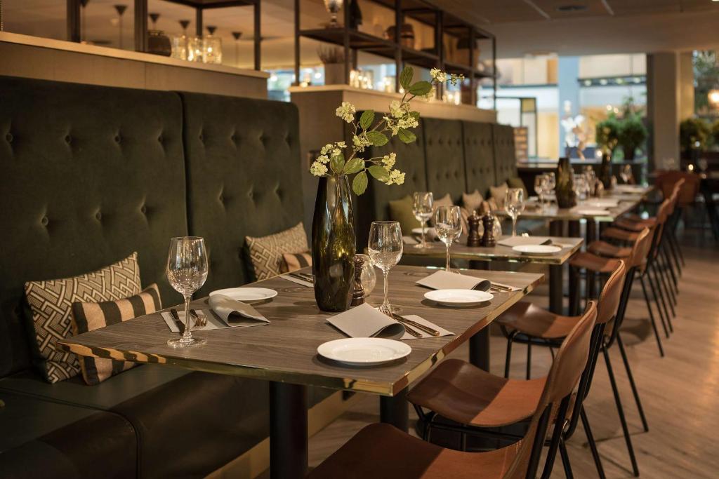 a long table in a restaurant with a vase of flowers at Scandic Hell in Hell