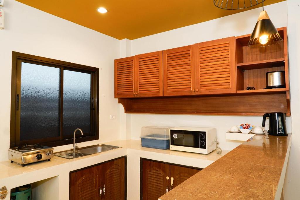 a kitchen with wooden cabinets and a sink and a microwave at Katanoi Resort in Kata Beach