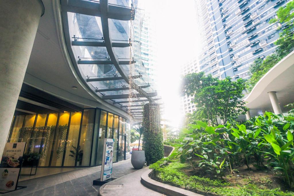 a building with a hallway with plants and buildings at Air Dream Den Good Vibes Makati Gym Swim Park Superfast Internet 3870 in Manila
