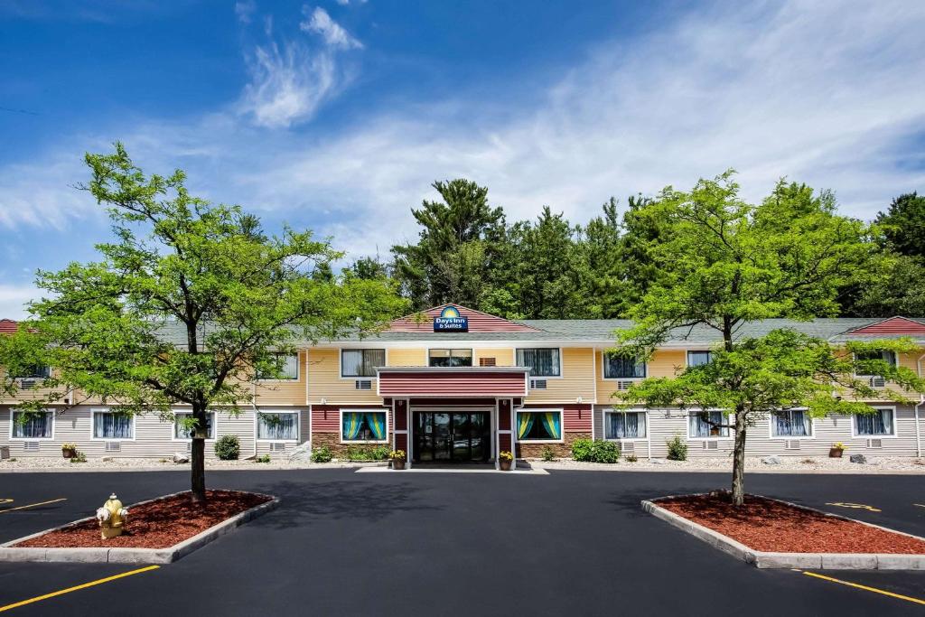 a hotel with trees in front of a building at Days Inn & Suites by Wyndham Stevens Point in Stevens Point