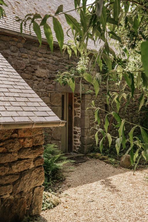 une maison en pierre avec une porte et un arbre dans l'établissement Les Maisons du Tuly, au Tronchet