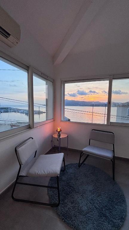 Cette chambre comprend deux chaises et des fenêtres offrant une vue sur l'océan. dans l'établissement Appartement vu sur mer, à La Seyne-sur-Mer