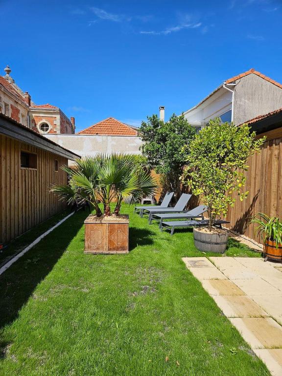 une cour avec une rangée de bancs dans l'herbe dans l'établissement maison avec studio independant dans le centre de soulac - 5306, à Soulac-sur-Mer