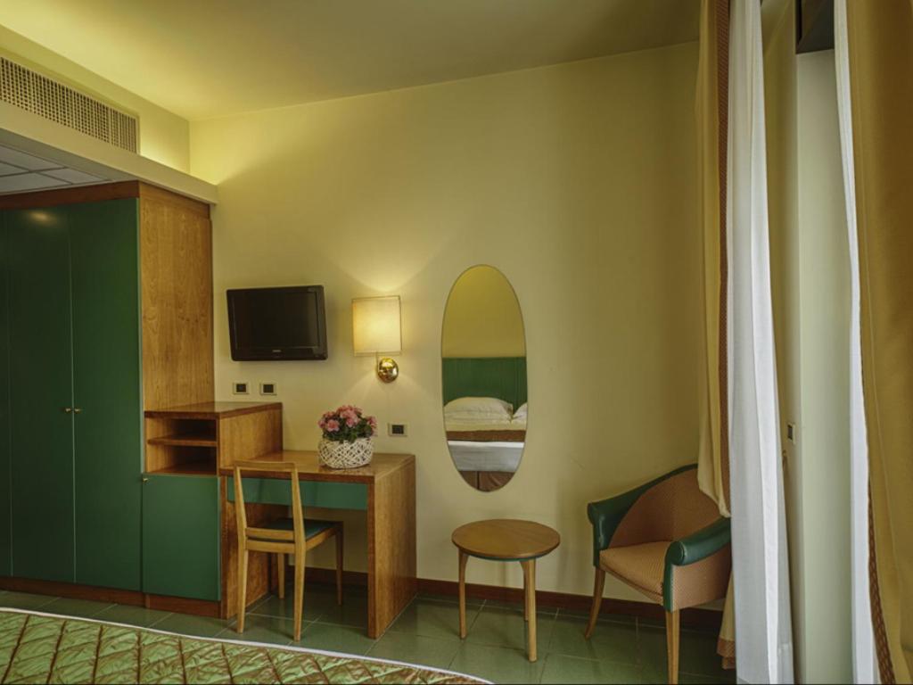 a room with a bed and a table and a mirror at Hotel Cristallo in Giulianova