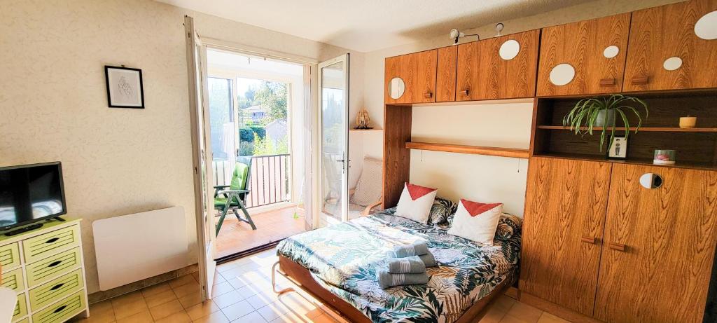 een slaapkamer met een bed en een tv en een balkon bij EDEN studio - Gréoux-Les-Bains in Gréoux-les-Bains