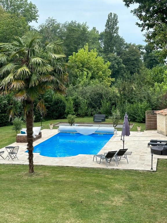 a swimming pool with a palm tree in a yard at La Vergnotte B & B in Saint-Antoine-de-Breuilh