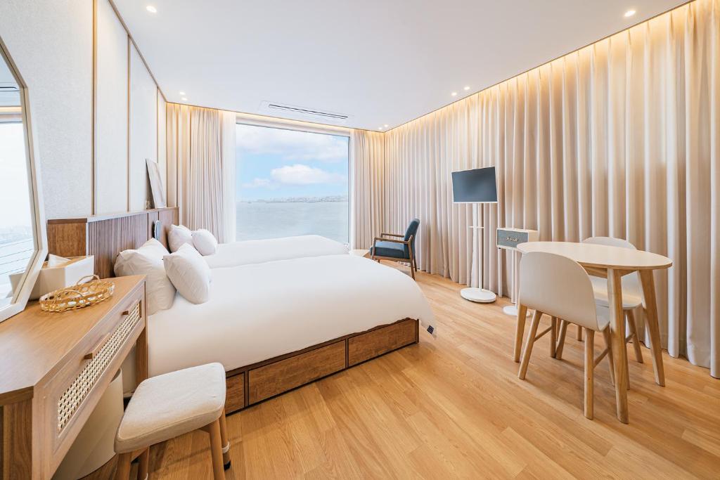 a hotel room with a bed and a desk and a table at Cony Ocean Suite Hotel in Jeju