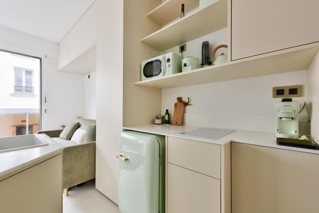 La cuisine blanche est équipée d'un réfrigérateur et d'un évier. dans l'établissement Cosy studio near Georges Brassens Parc, à Paris