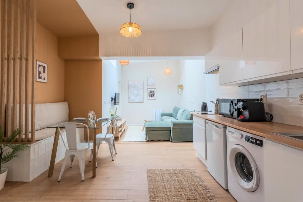une cuisine avec une machine à laver et une table avec des chaises dans l'établissement Appartement une chambre sur la place Sébastopol, à Lille