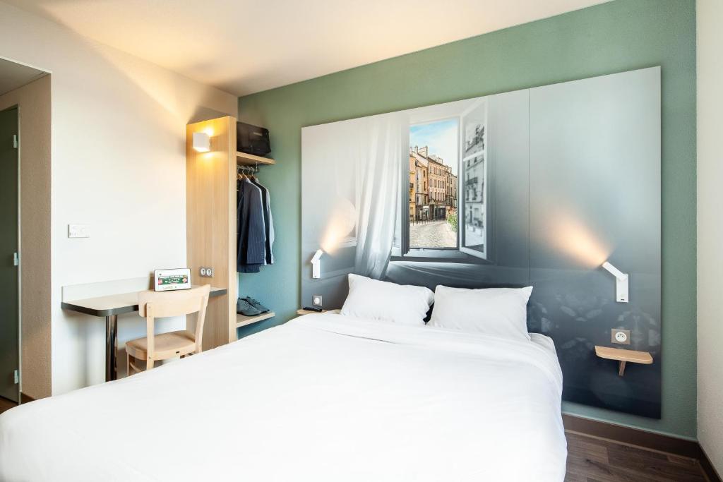 a bedroom with a large white bed and a window at B&B HOTEL Meaux in Meaux
