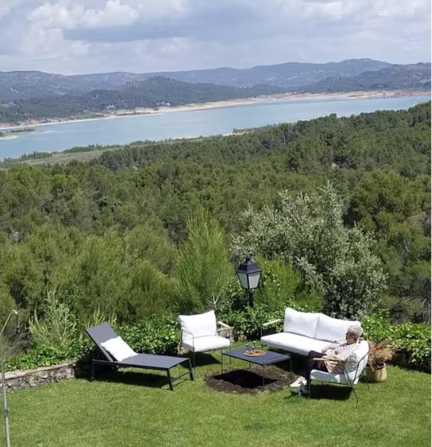 a man sitting on a lawn with two chairs and a table at Increible casa de campo, 5 DORM, MARCO INCOMPARABLE in Pareja
