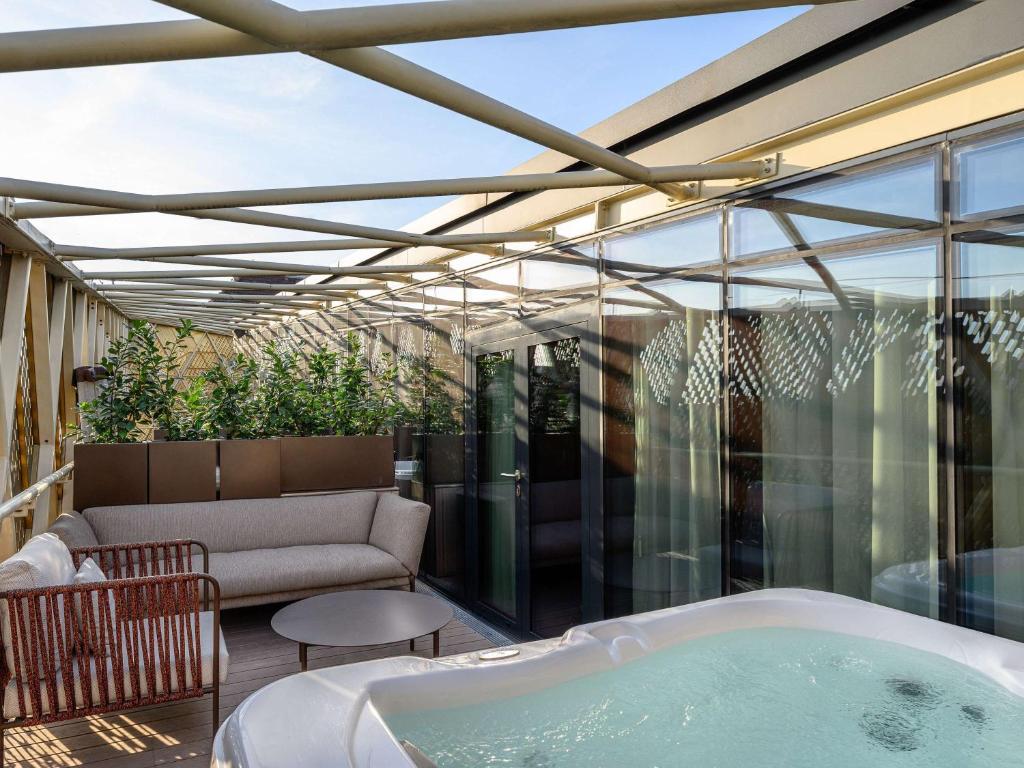 a hot tub on a patio with a couch at Pullman Budapest in Budapest