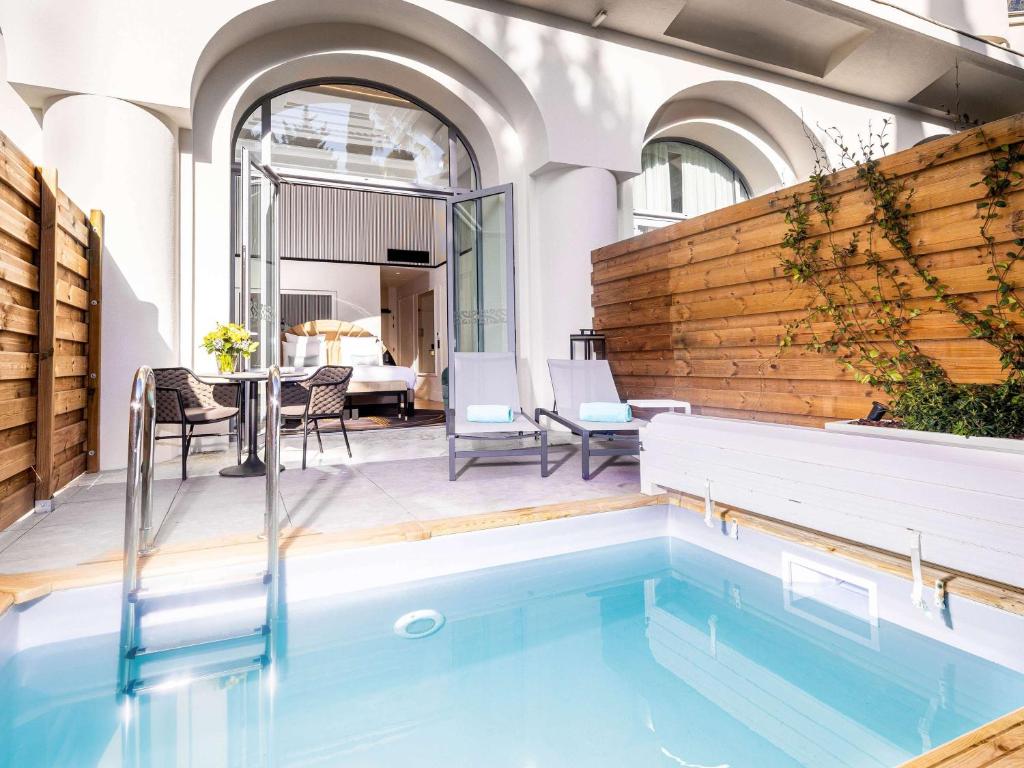 a swimming pool in the middle of a patio with a table and chairs at The 1932 Hotel & Spa Cap d'Antibes - MGallery Collection in Juan-les-Pins