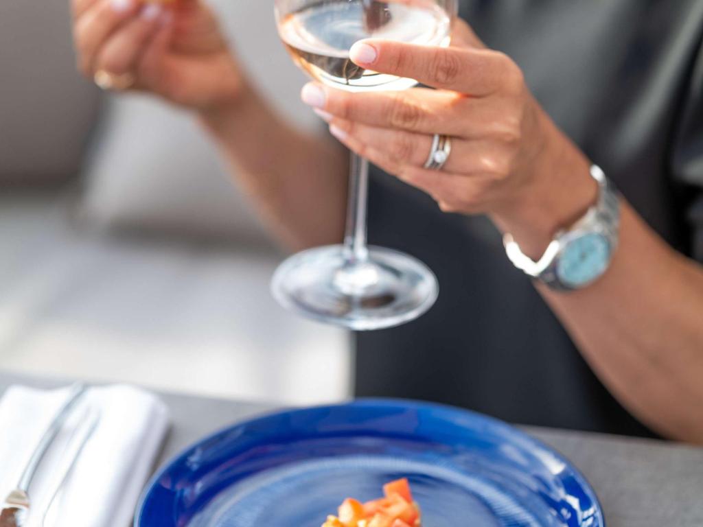 a person holding a wine glass next to a plate of food at The 1932 Hotel & Spa Cap d'Antibes - MGallery Collection in Juan-les-Pins