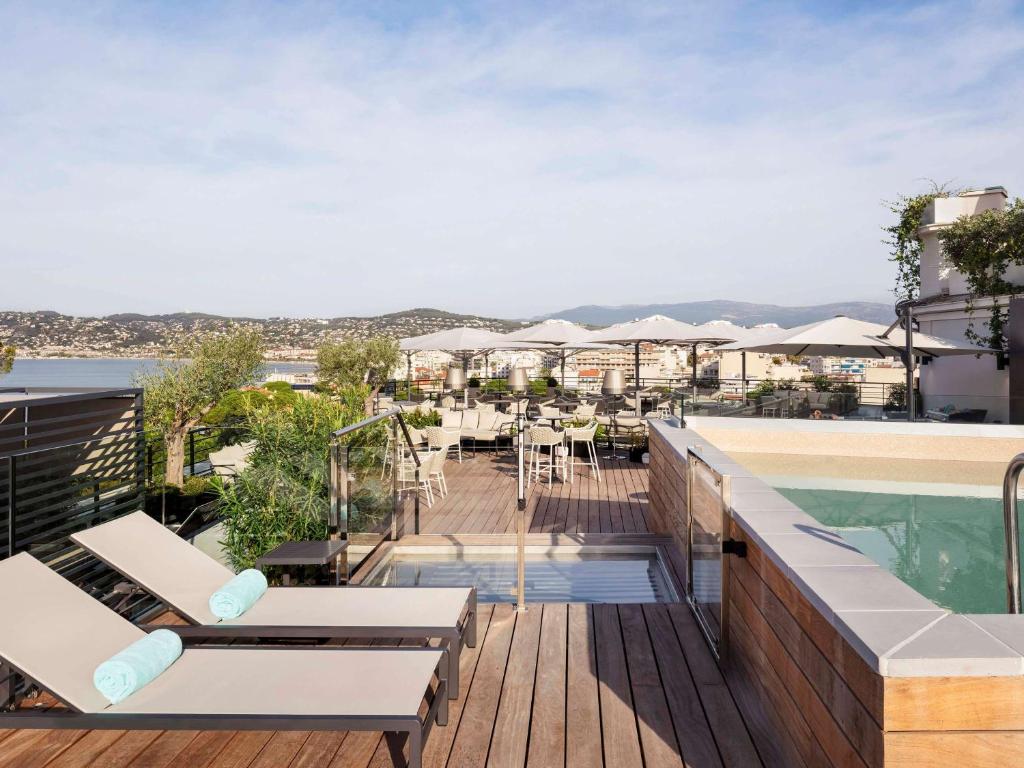 a balcony with a pool and tables and chairs at The 1932 Hotel & Spa Cap d'Antibes - MGallery Collection in Juan-les-Pins