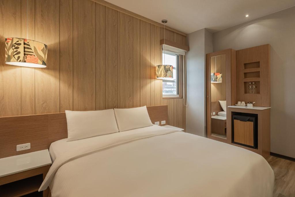 een slaapkamer met een groot wit bed en een badkamer bij Kindness Hotel - Chihkan Tower Branch in Tainan