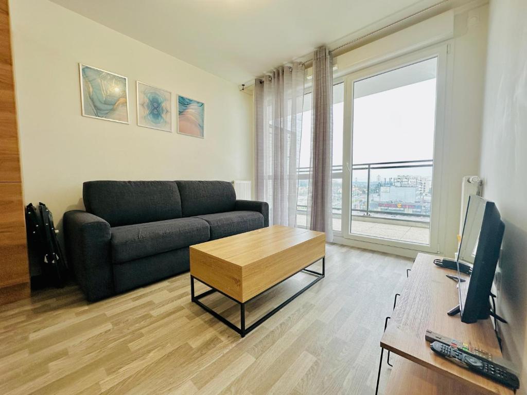 un salon avec un canapé et une table dans l'établissement Agréable 2 pièces avec balcon et Parking transports by immo kit bnb, à Sarcelles
