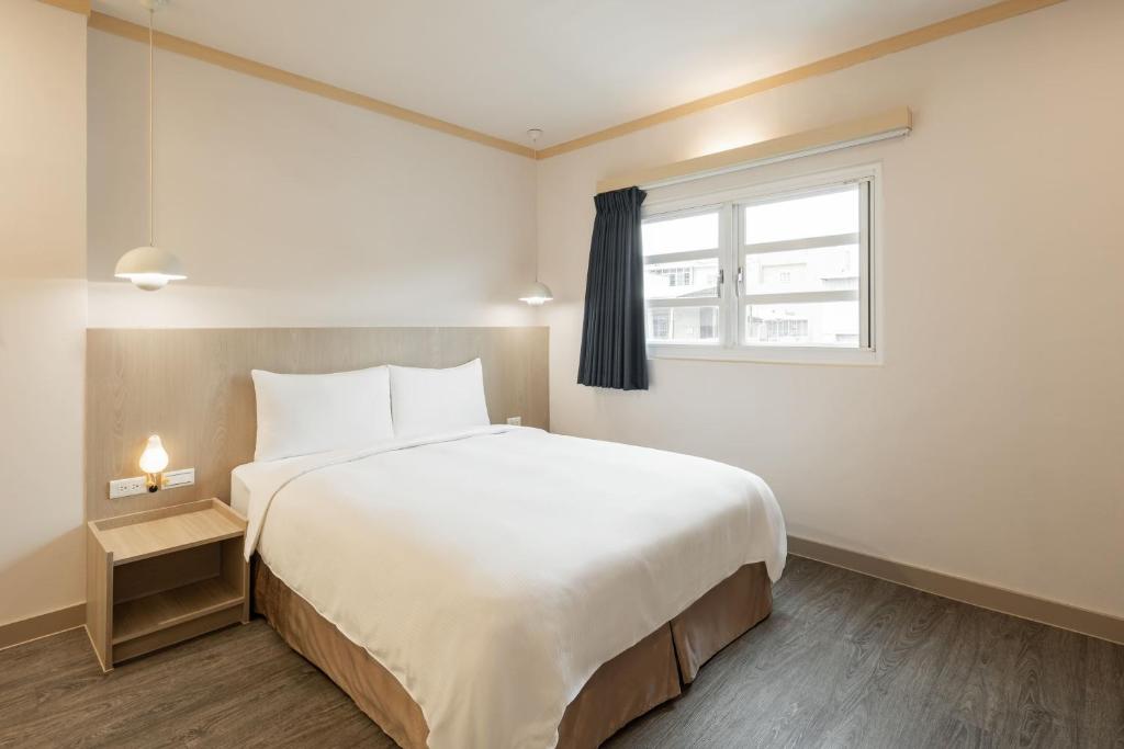 台南市にあるKindness Hotel - Tainan Mingsheng Branchの大きな白いベッドと窓のある寝室