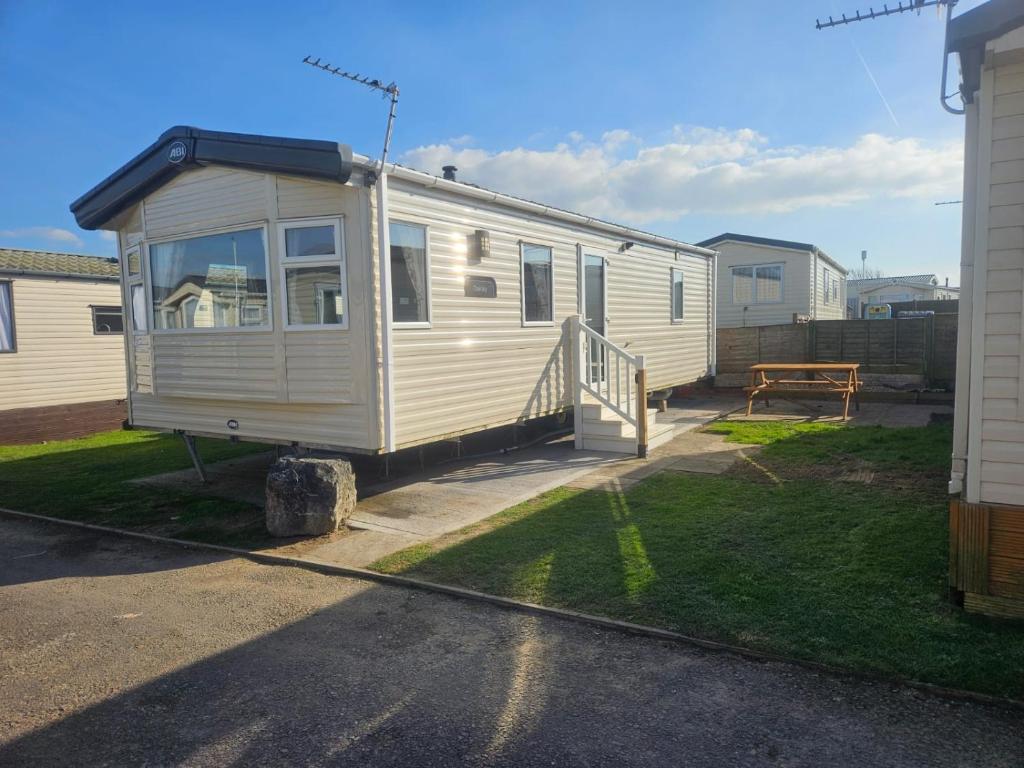 a mobile home parked in a yard next to a house at 6 Berth Caravan with garden - Brightholme Holiday Park in Brean