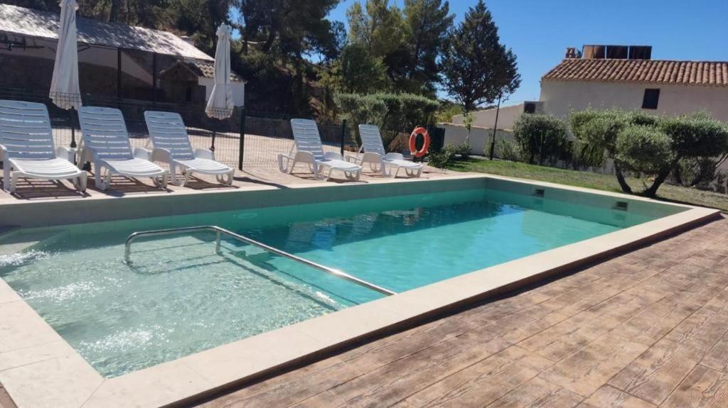 a large swimming pool with chairs and a swimming pool at ENTRESIERRAS Apartamentos rurales con chimenea, barbacoa y espacio para eventos in Cazorla