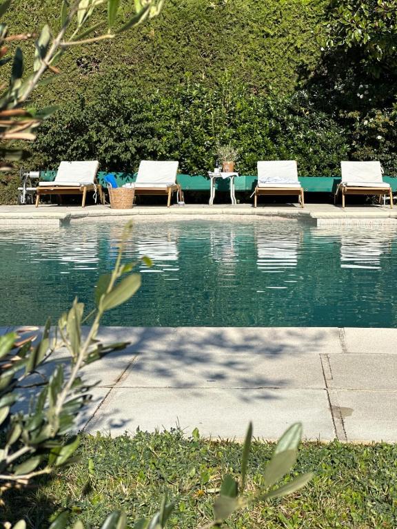 - deux chaises longues et une table à côté de la piscine dans l'établissement Le Lagon Vert, à Pernes-les-Fontaines