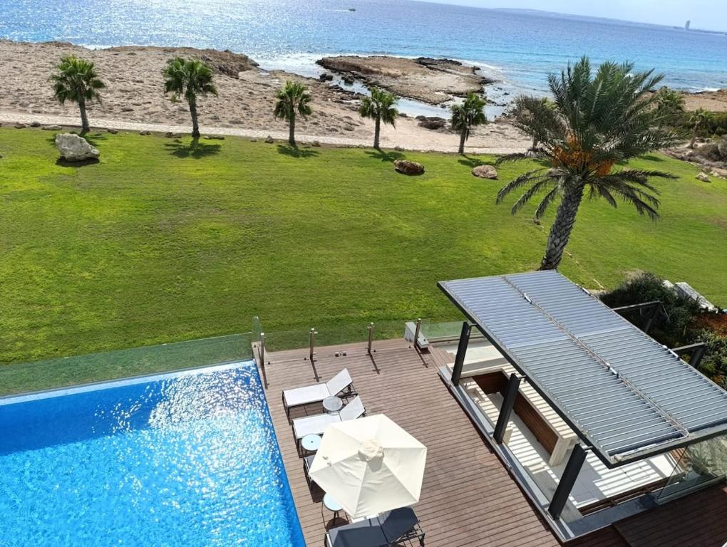 a swimming pool with a deck and a view of the beach at Beachfront Luxury Villa Glory in Ayia Napa