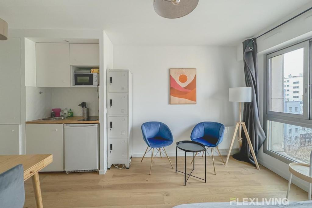 une cuisine et deux chaises bleues dans une pièce dans l'établissement Flexliving - studio - versailles, à Paris