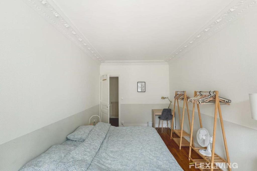 une chambre avec un lit dans une pièce blanche dans l'établissement Flexliving - room - Prague, à Paris