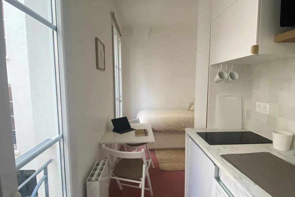 une petite cuisine blanche avec un lit en arrière-plan dans l'établissement Flexliving - Studio - Paradis, à Paris