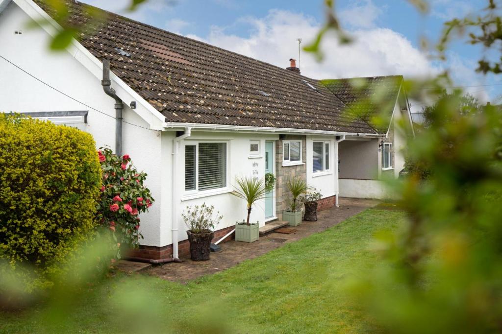 una casa bianca con piante in un cortile di The Willows - 2 Bedroom Cottage - Oxwich a Oxwich