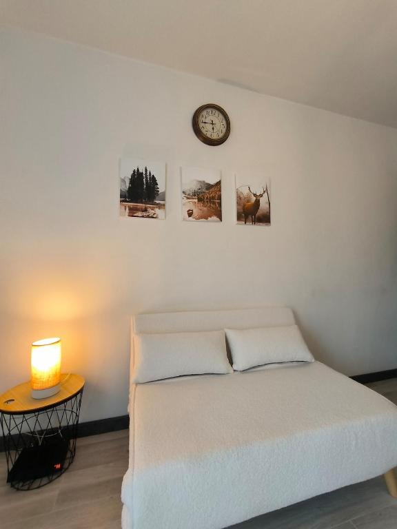 une chambre avec un lit et une horloge au mur dans l'établissement Joli Studio lumineux Centre ville Parking gratuit, à Pau