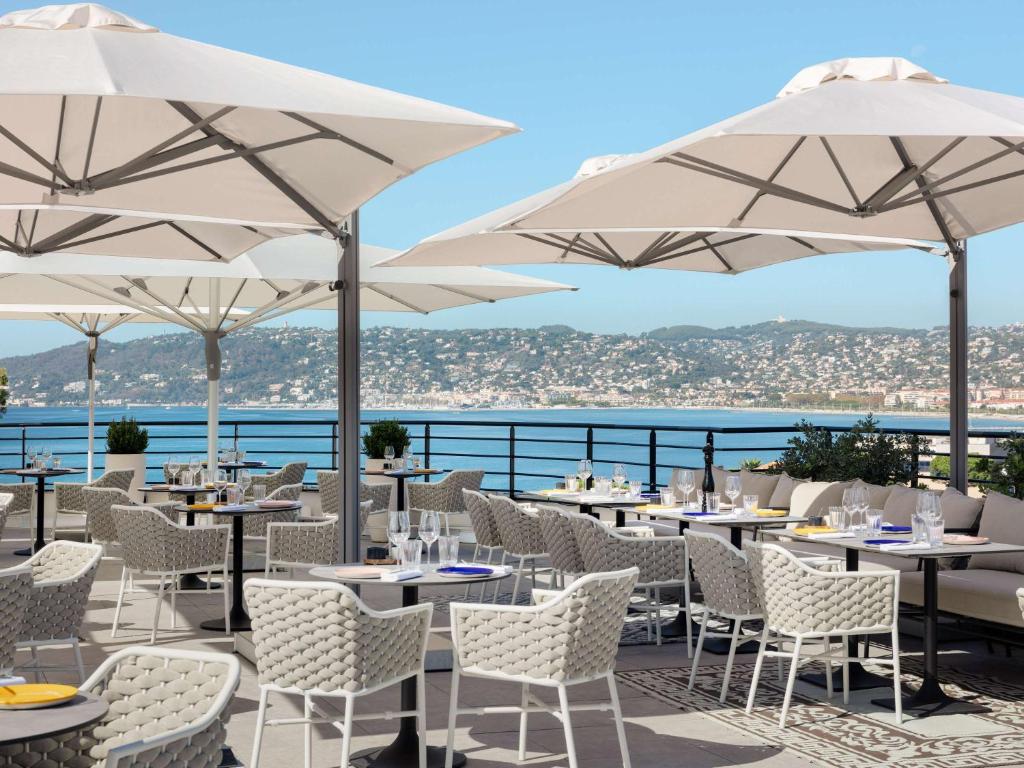 a restaurant with tables and chairs and umbrellas at The 1932 Hotel & Spa Cap d'Antibes - MGallery Collection in Juan-les-Pins