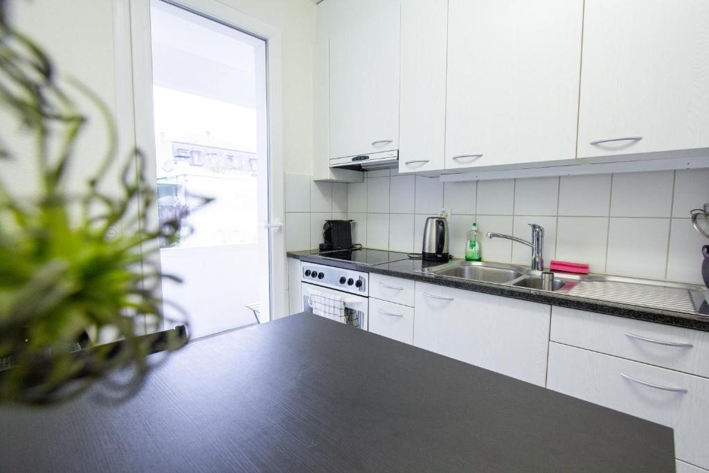 a kitchen with white cabinets and a black counter top at Gemütliche Wohnung Nähe Uni in Basel